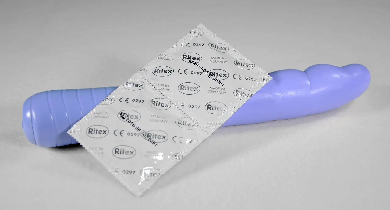 Lilla vibrator og en kondompakke på en lys flade